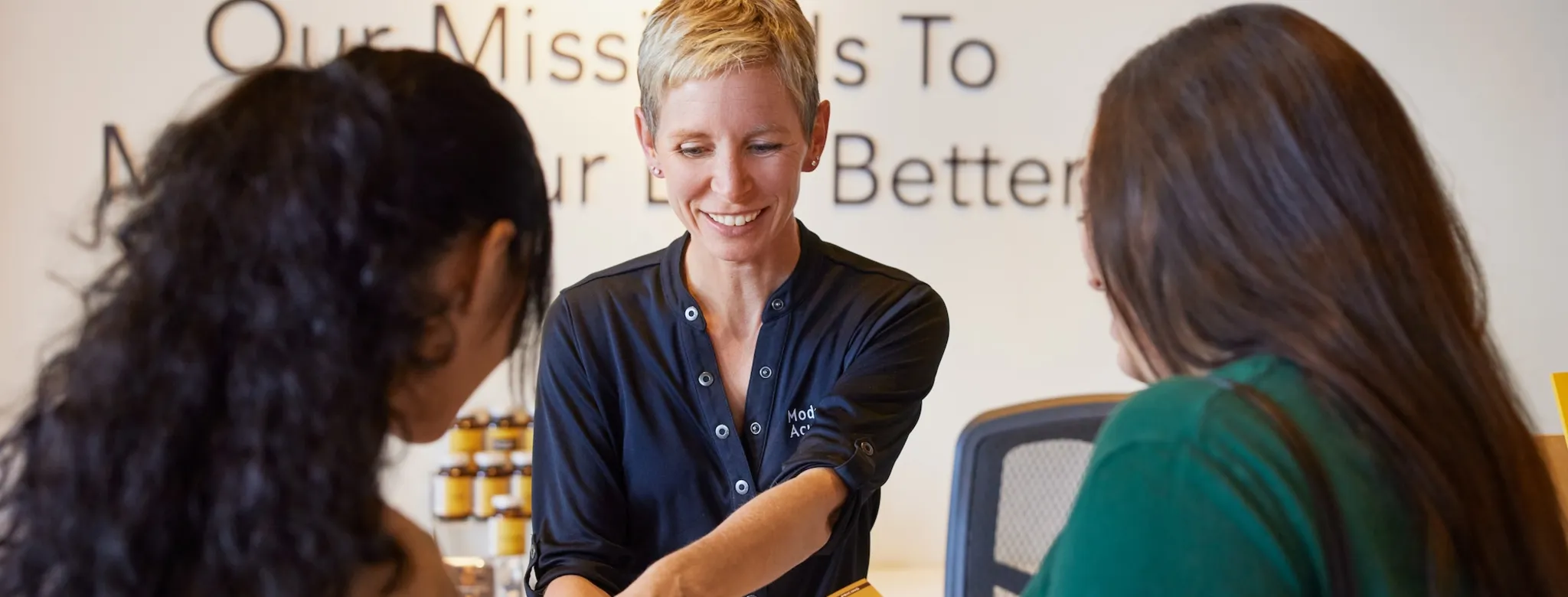 2 customers speaking to a receptionist at an acupuncture business