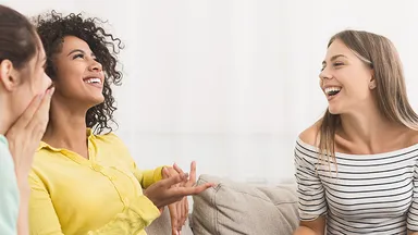 Three women talking on a couch. 