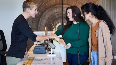woman helping two women at front desk at business